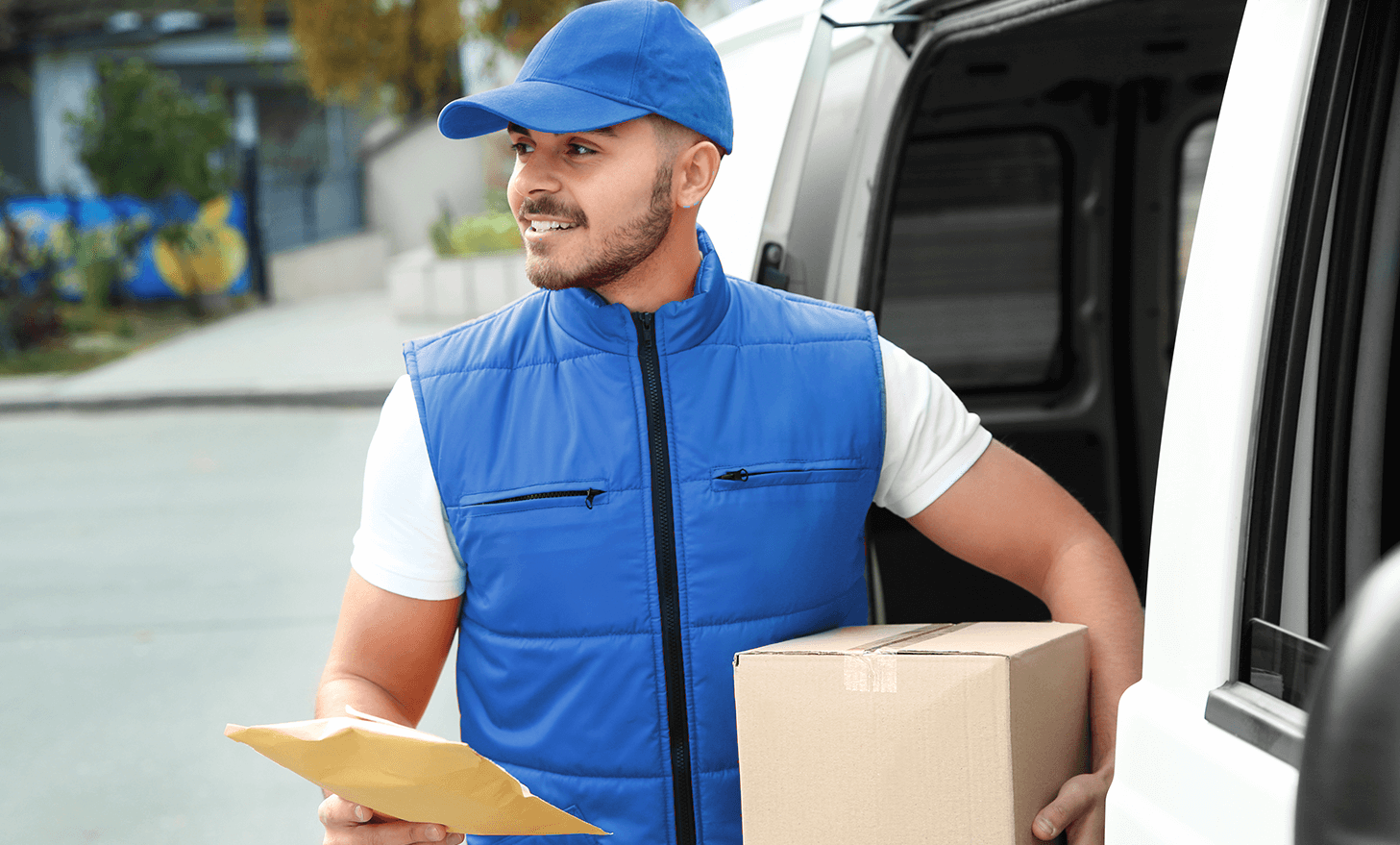 Background image of delivery driver holding packages in doorway of van